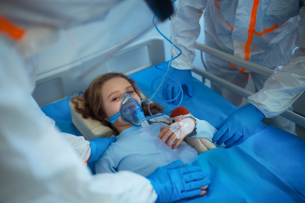 Una niña aparece acostada en una cama de hospital, con oxígeno, y rodeada de sanitarios